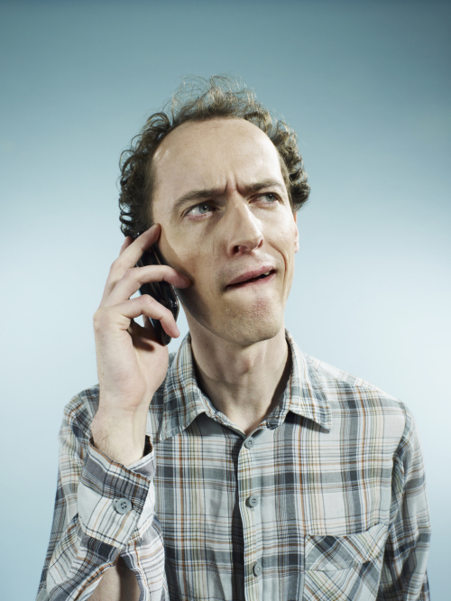 A man using a mobile phone with a confused look on his face