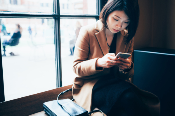 Businesswoman using cell phone in library