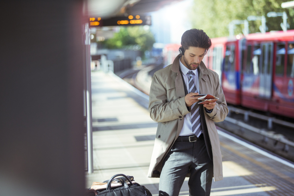 Businessman using cell phone in train station