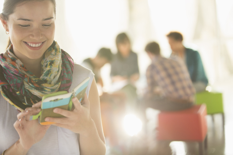 Happy businesswoman text messaging with cell phone outside meeting