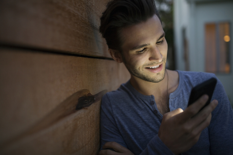 Man texting with cell phone on dark patio