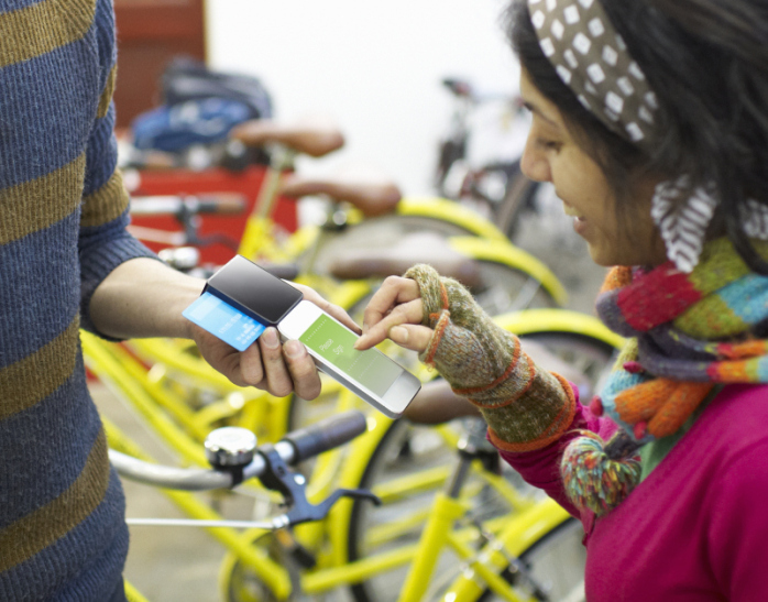 Woman using mobile payment device in bike shop.