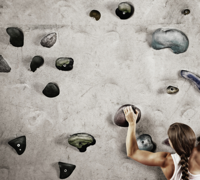 Female climber holding onto hold on climbing wall