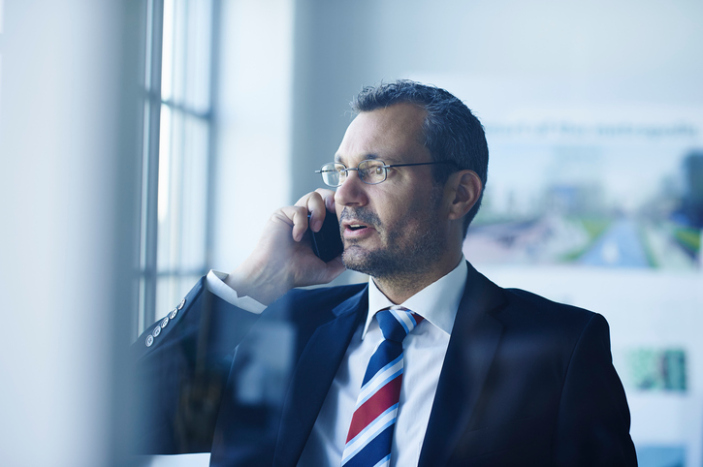 Business man chatting on smartphone whilst looking out of window