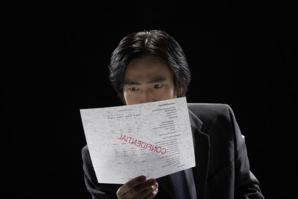 Businessman reading document stamped confidential, close-up