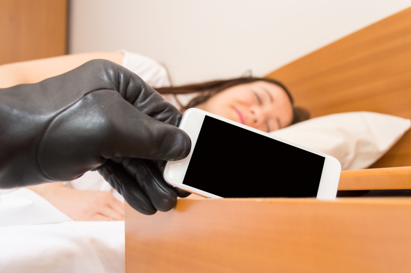 robber steals the smartphone of the nightstand while woman sleeps deeply