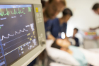 Heart rate monitor, patient and doctors in background in intensive care unit