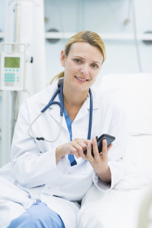 Smiling woman doctor holding a smartphone in a hospital room
