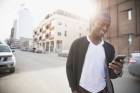 Smiling man texting on cell phone urban street