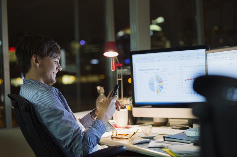 Businessman with cell phone working late in office