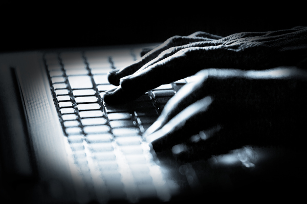 Concept photo in high contrast black and white of hacker's fingers on keyboard