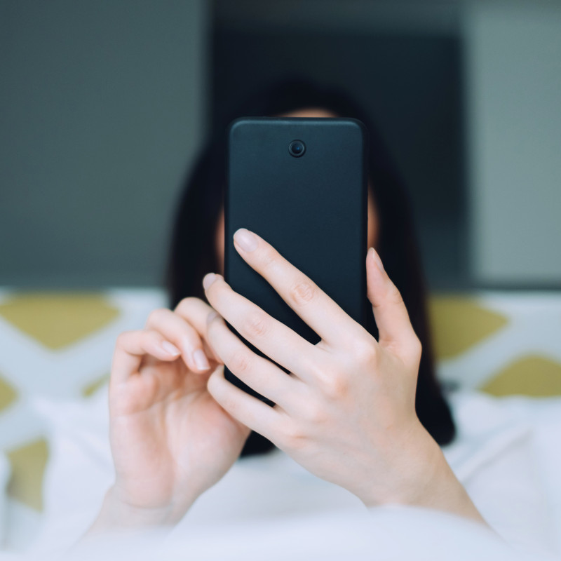 Portrait of woman using mobile phone while lying on bed