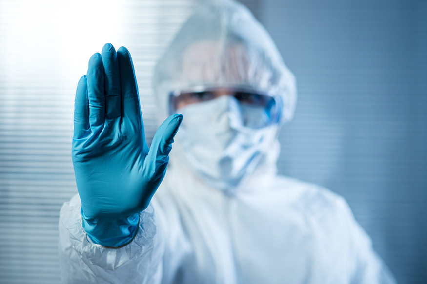 Scientist with hand raised in hazmat protective suit, stop concept.